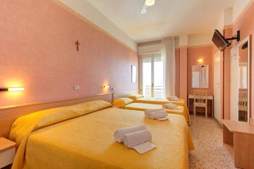 a bedroom with two beds and a cross on the wall at Hotel Nella in Rimini