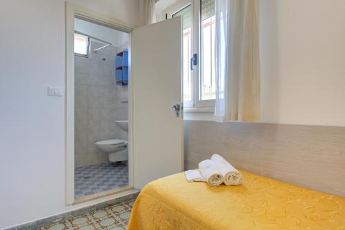 bagno con letto e asciugamani di Hotel Nella a Rimini