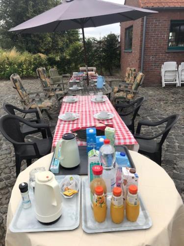 a long table with drinks on it with an umbrella at Ferme du Charme in Moustier