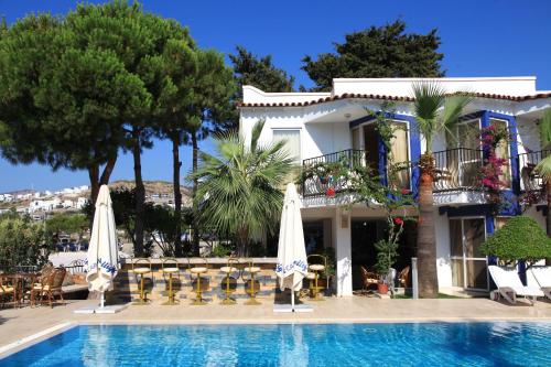 a house with a swimming pool with umbrellas at Catamaran Hotel in Gundogan