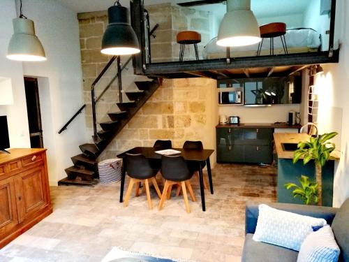 a living room with a table and chairs and a staircase at La Maison Grivolas Appartements et Maison d'hôtes in Avignon