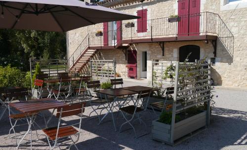 un patio avec tables, chaises et un parasol dans l'établissement LE RELAIS D'ARZAC, à Cahuzac-sur-Vère