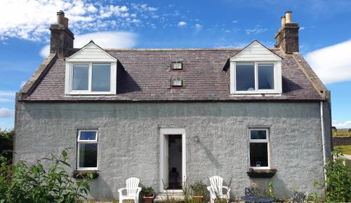 a house with two white chairs in front of it at West Gallaton Farmhouse in Stonehaven
