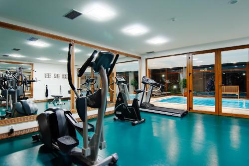 a gym with cardio machines and a swimming pool at Hotel International in Tatranská Lomnica