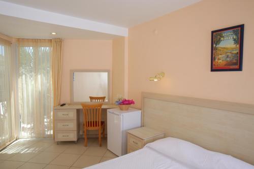 a bedroom with a bed and a desk and a chair at Catamaran Hotel in Gundogan