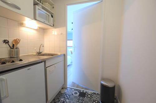 a kitchen with a door that leads to a sink at Les Studiantes - T1 32 m² hypercentre gares/métro in Lille