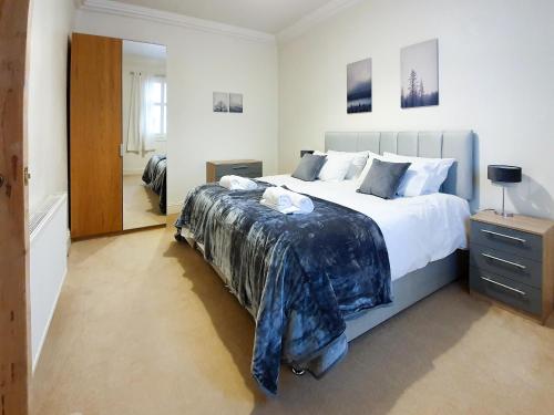 a bedroom with a large bed with a blue blanket at Linburn House Apartment in Dunfermline