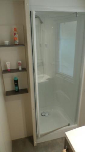 a shower with a glass door in a bathroom at Mobilhome dans Camping les Sables d'or in Cap d'Agde