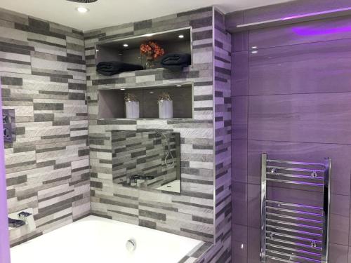 La salle de bains est pourvue d'un mur violet et gris. dans l'établissement Livit Serviced Apartments, à Bradford