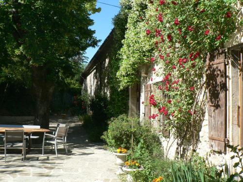 un giardino con tavolo e fiori su un edificio di Le Moulinage a Saint-Thomé