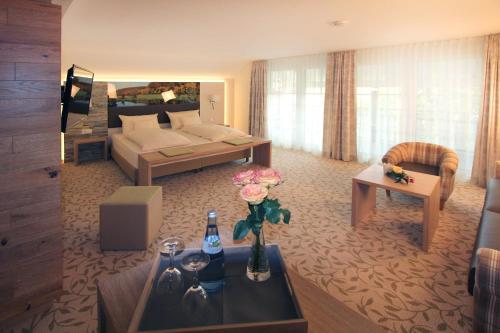LauchheimにあるLandgasthof Sonneのベッドとリビングルームが備わる広いホテルルームです。