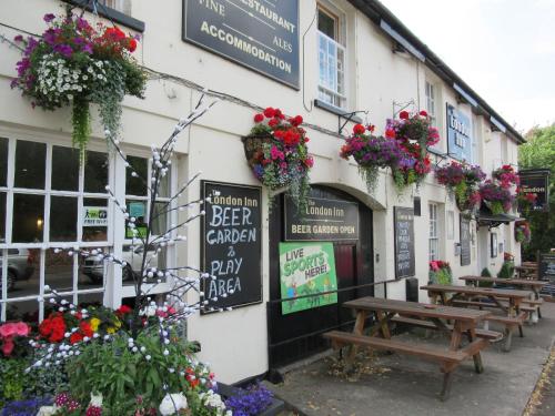 pub ogrodowy z kwiatami na boku budynku w obiekcie The London Inn w mieście Cheltenham