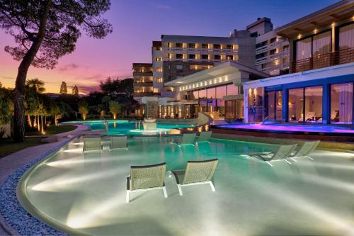 a swimming pool with chairs and a building at Esplanade Tergesteo - Luxury Retreat in Montegrotto Terme