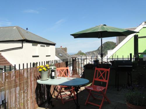 a table and chairs and an umbrella on a patio at Seaview Grade II Listed Cottage with large Sun Terrace 'The Old Eclectick' in Ilfracombe