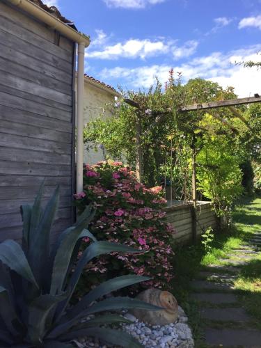a garden with pink flowers next to a house at Accacia Home in Ferrières