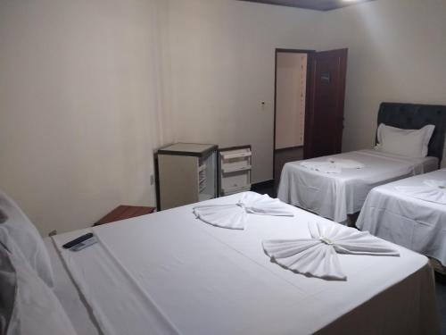 a room with two beds with white sheets at HOTEL PRAIA DA PAIXÃO in Prado