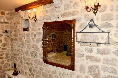 a stone wall with a mirror in a room at Zupan B studio apartman Krk in Krk