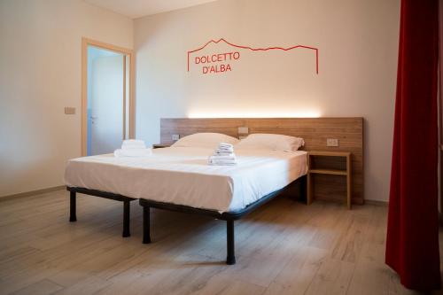 a bed in a room with a sign on the wall at Vino e Turismo in San Defedente di Cervasca