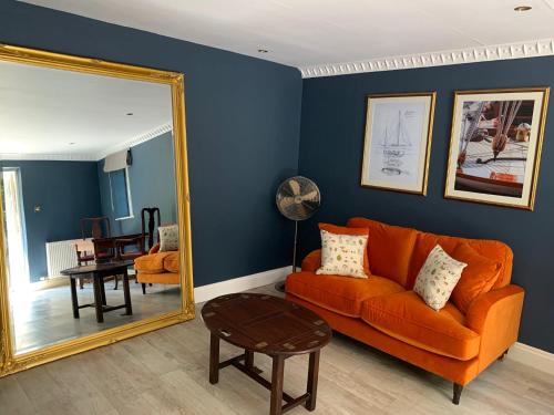 a living room with an orange couch and a mirror at Boscundle Manor in St Austell