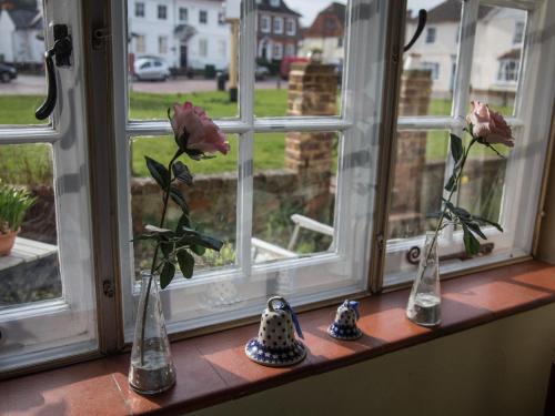 una fila de jarrones sentados en un alféizar de la ventana con rosas en The Old Manor House B & B en Brasted