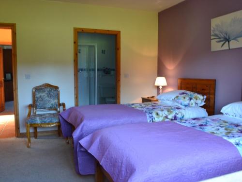 a bedroom with two beds and a chair at Manorview B&B in Cookstown