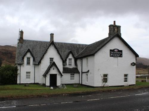 una casa blanca con un techo negro al lado de una carretera en Luib Hotel en Killin