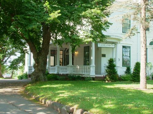 una casa bianca con un portico e un albero di Marshlands Inn a Sackville