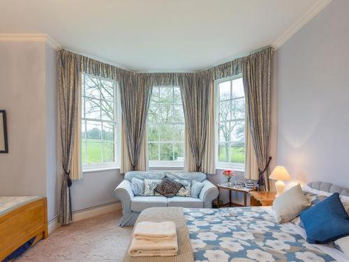 ein Schlafzimmer mit einem Bett, einem Sofa und Fenstern in der Unterkunft Marshwood Farm B&B and Shepherds Hut in Dinton