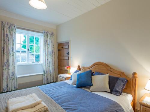 um quarto com uma cama com lençóis azuis e uma janela em The Cottage Marshwood Farm em Dinton