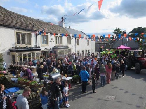 a large crowd of people standing in a street at The Miners Arms in Eyam