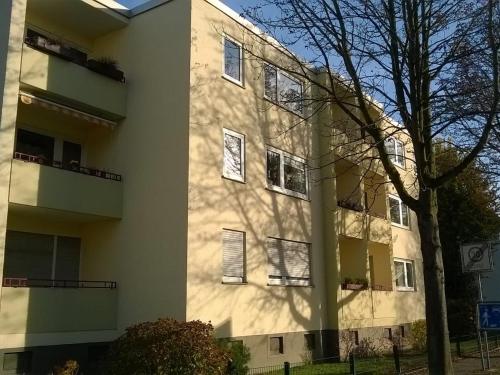 a white building with a tree in front of it at Fewo Neukirchen mit Balkon in Neukirchen-Vluyn