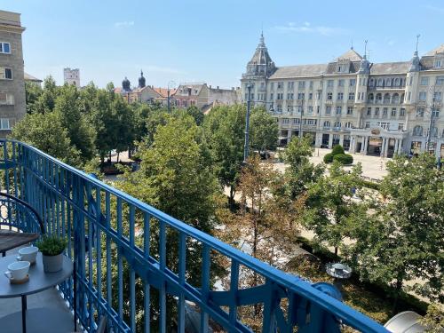 a balcony with a blue railing and buildings at Visit Debrecen Apartman in Debrecen