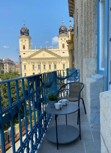 a table and chair on a balcony with a building at Visit Debrecen Apartman in Debrecen