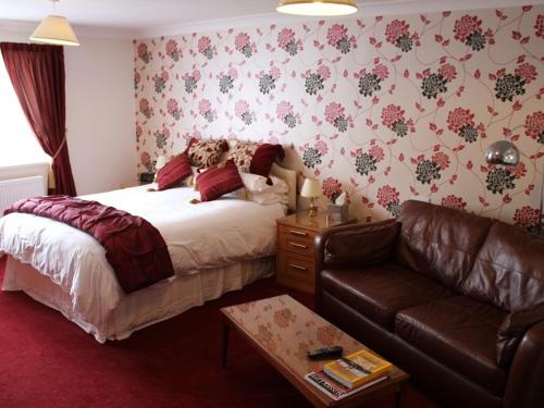 a bedroom with a bed and a leather couch at Merton House in Worthing