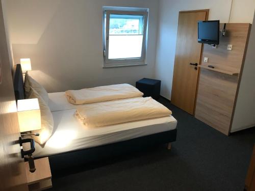 a bedroom with two beds and a window and a television at Motel Herbold in Knüllwald