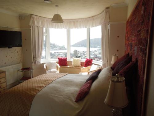a bedroom with a large bed with a large window at Mounthaven Guest House in Dartmouth