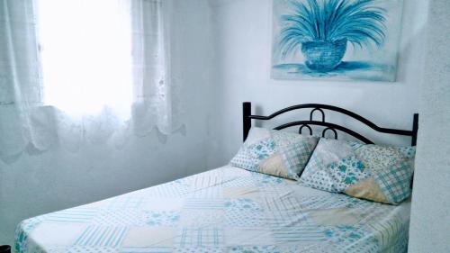 um quarto com uma cama com uma planta na parede em Cantinho do sossego em Caraguatatuba