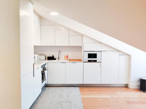 eine Küche im Dachgeschoss mit weißen Schränken und einer Treppe in der Unterkunft FLH Downtown Modern Apartment in Lissabon