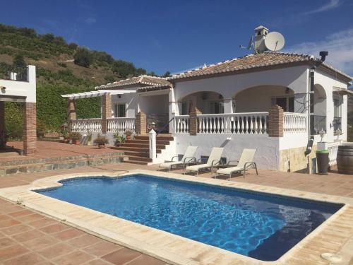 a villa with a swimming pool in front of a house at Villa Sunshine Countryside Resort in Frigiliana