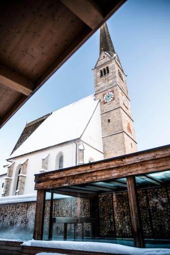 a church with a tower with a clock on it at Lifestyle Hotel eder in Maria Alm am Steinernen Meer