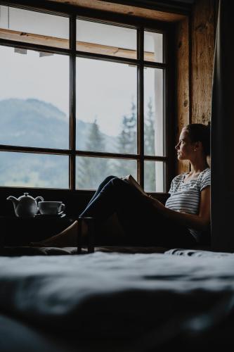 a woman sitting in a window reading a book at HOTEL SEPP - Alpine Boutique Hotel - Adults Only ab 21 Jahre in Maria Alm am Steinernen Meer