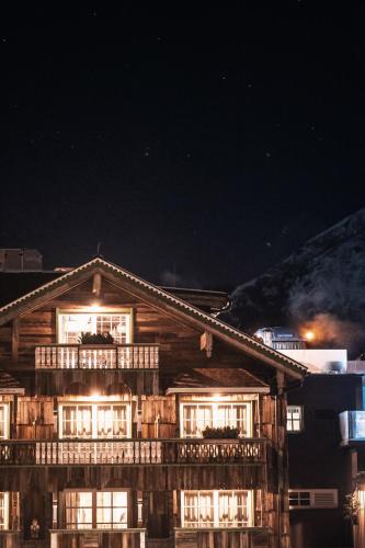 a wooden house with a balcony at night at HOTEL SEPP - Alpine Boutique Hotel - Adults Only ab 21 Jahre in Maria Alm am Steinernen Meer