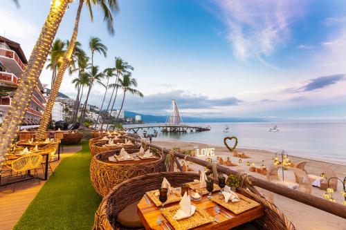 a restaurant on the beach with palm trees and the ocean at Playa Los Arcos Hotel Beach Resort & Spa in Puerto Vallarta