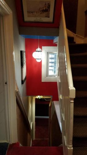 a staircase in a house with a red wall at City View Hotel Roman Road in London