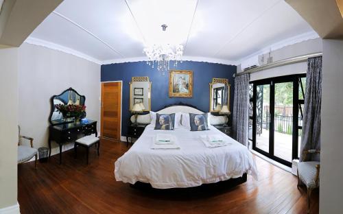 een slaapkamer met een bed en een blauwe muur bij Le Grant Guesthhouse in Kroonstad