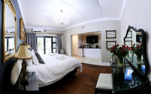 a bedroom with a bed and a table with flowers at Le Grant Guesthhouse in Kroonstad