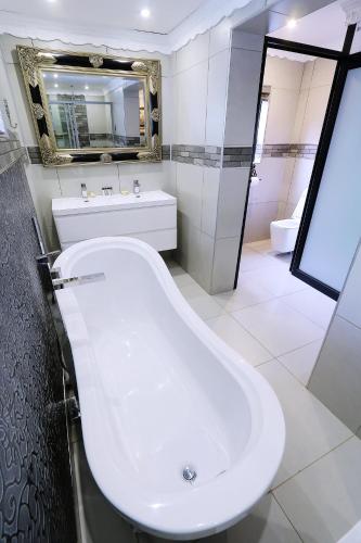 a white bathroom with a tub and a sink at Le Grant Guesthhouse in Kroonstad