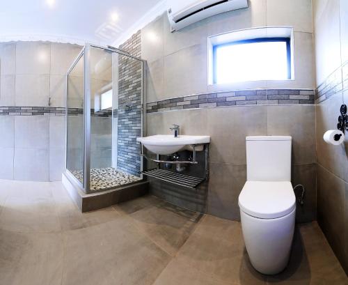a bathroom with a shower and a toilet and a sink at Le Grant Guesthhouse in Kroonstad