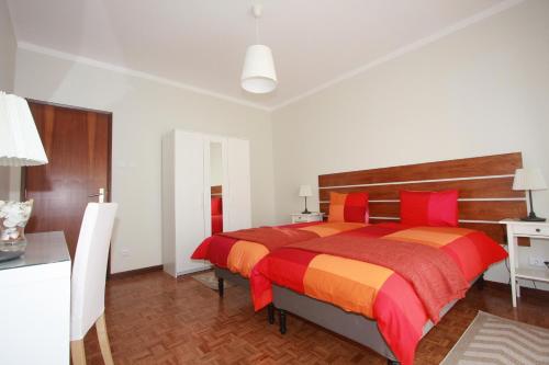una camera con un grande letto rosso e arancione di A Casa do Centro a Peniche