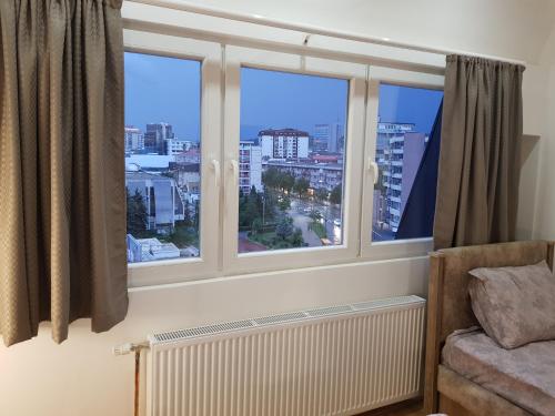 a room with three windows with a radiator and a view at Prishtina Newborn ABC room in Pristina